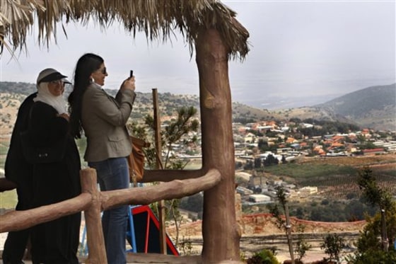 A Lebanese woman takes pictures with her mobile phone of an Israeli settlement which is seen in the bacground, at a newly opened border park, at the Lebanese border village of Maroun el-Rass on the Lebanon-Israel border.